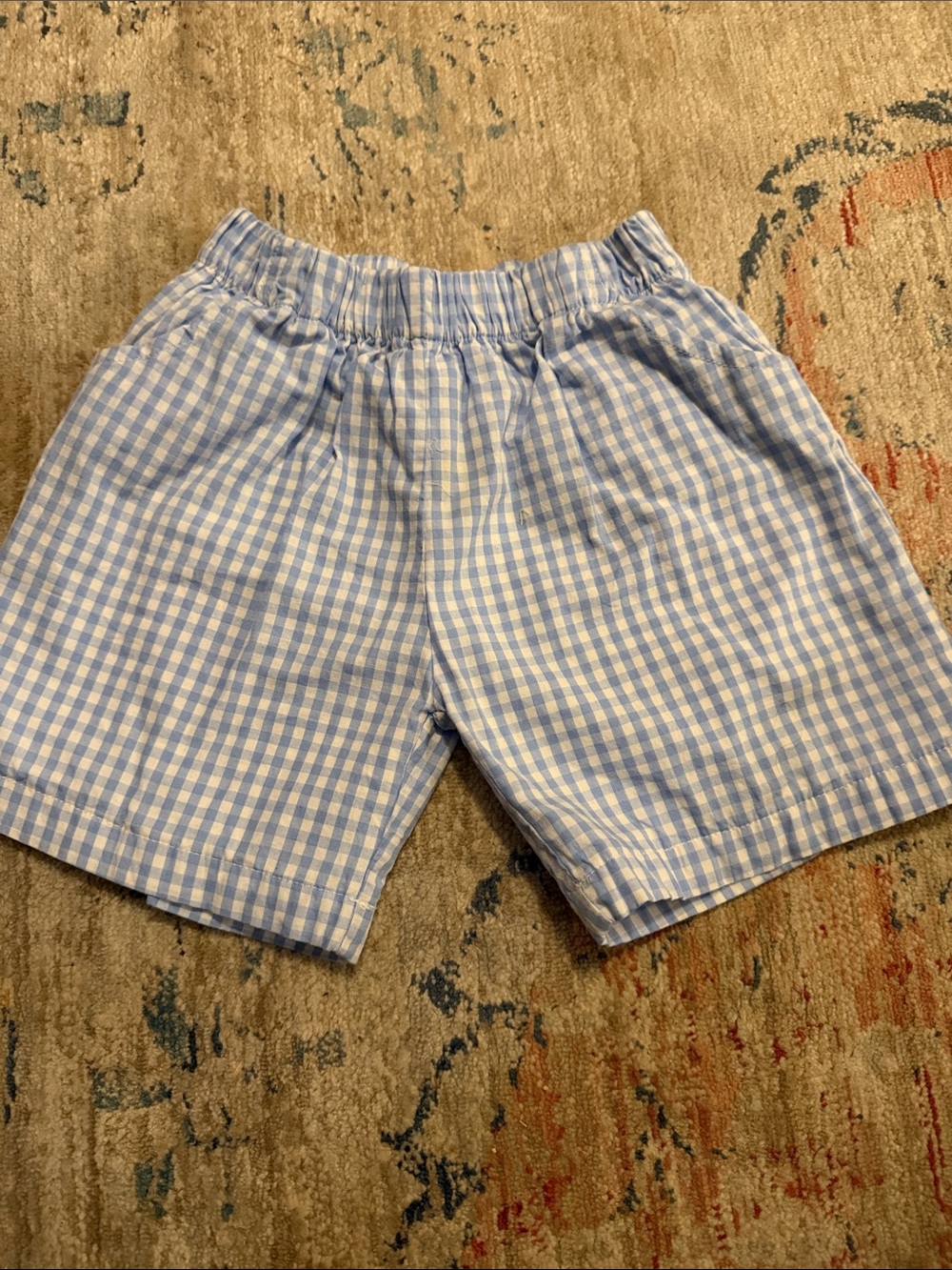 Kids pull on gingham shorts in light blue and white.